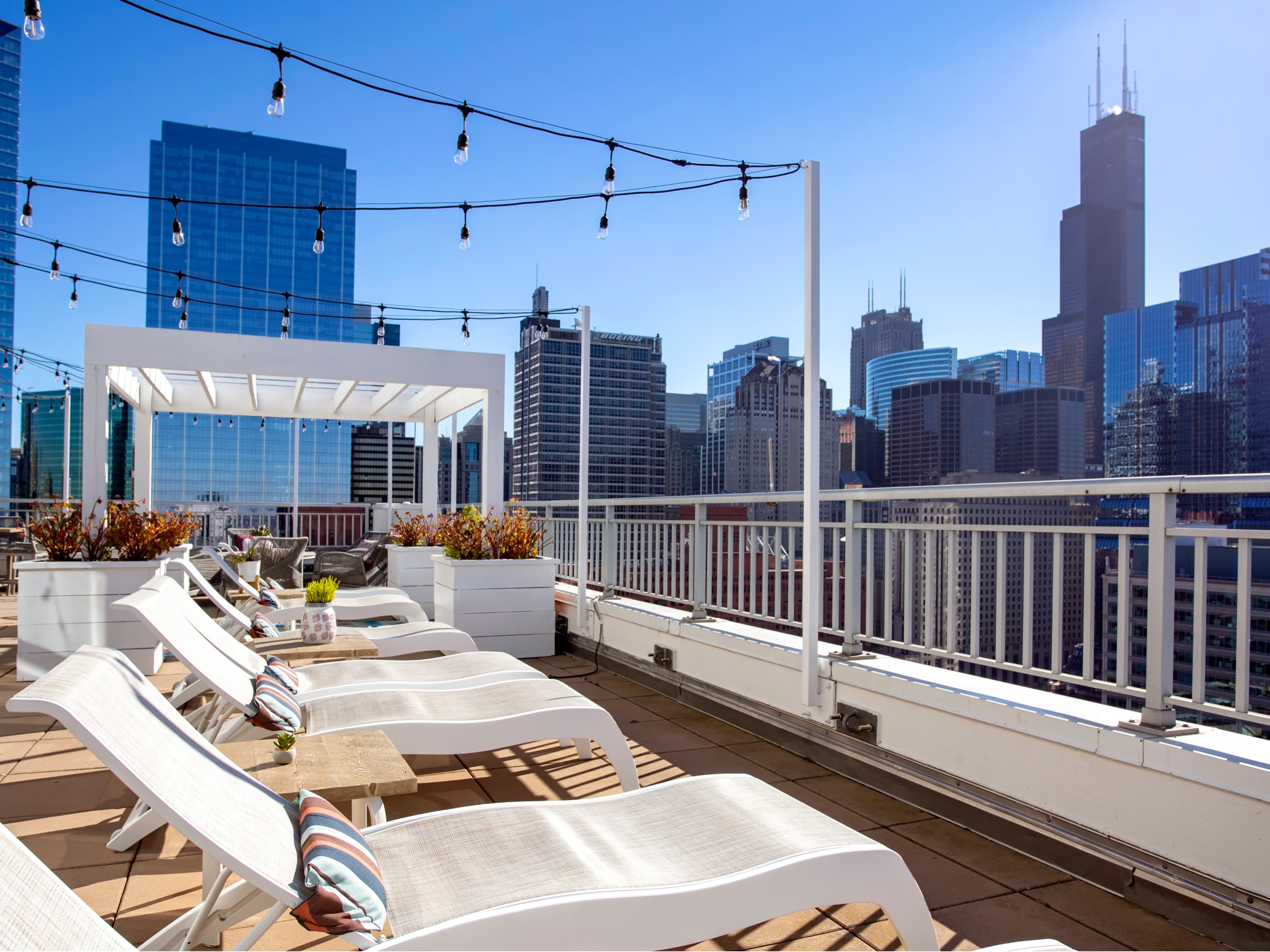 Professional photography shot of an apartment property's rooftop deck with loungechairs overlooking the city